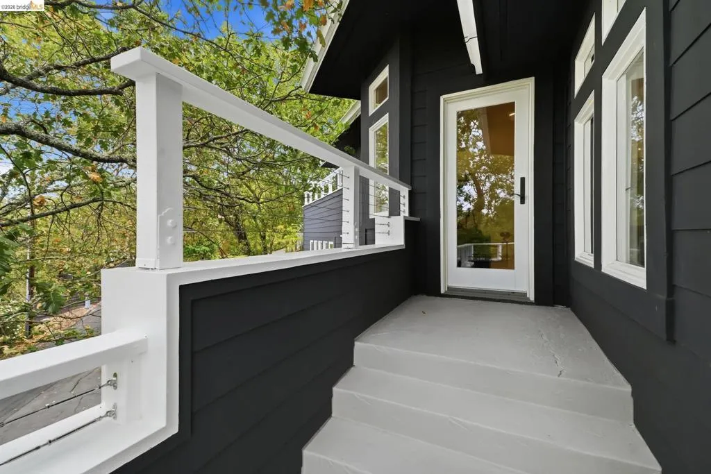 Exterior featuring dark horizontal siding, white trim windows, white full-lite entry door, and a white cable railing system Exterior featuring dark horizontal siding, white trim windows, white full-lite entry door, and a white cable railing system