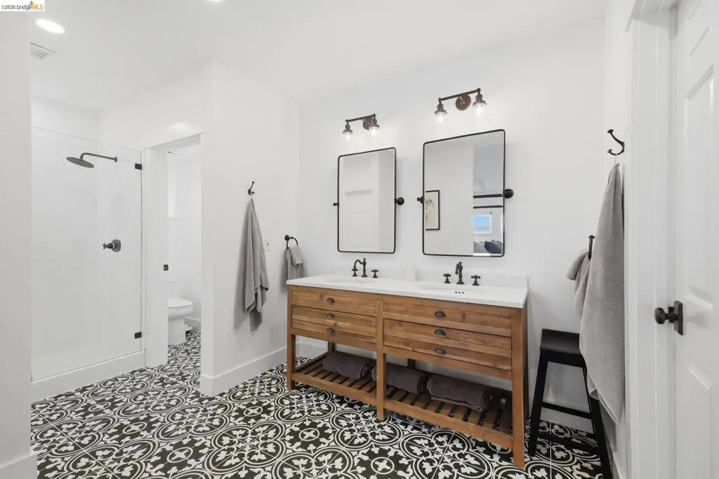 Dual vanity with a stone countertop and integrated sinks, complemented by two rectangular mirrors Dual vanity with a stone countertop and integrated sinks, complemented by two rectangular mirrors