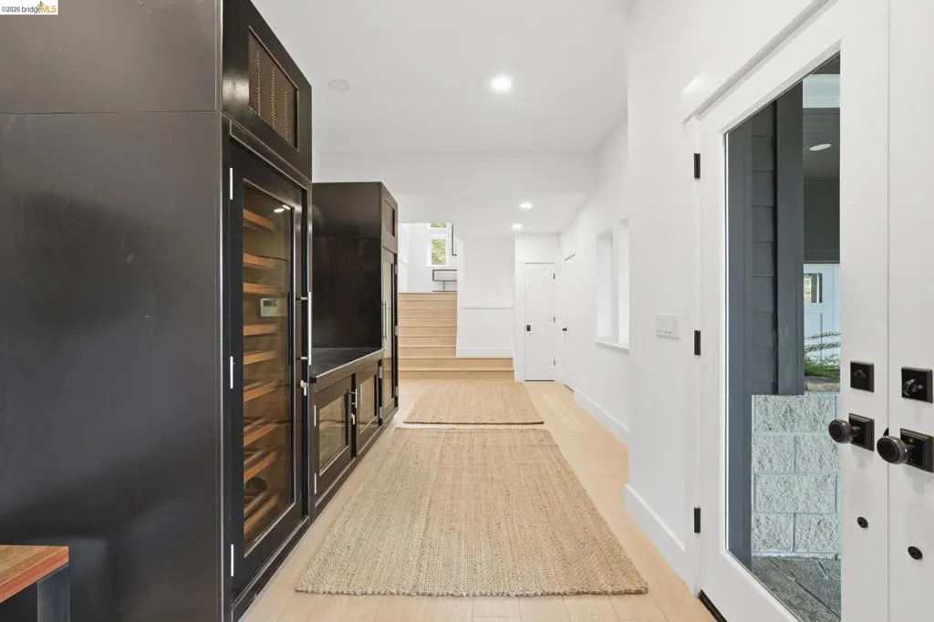 Entryway featuring wood-finish flooring, recessed lighting, white walls, and a built-in beverage cooler with display doors Entryway featuring wood-finish flooring, recessed lighting, white walls, and a built-in beverage cooler with display doors