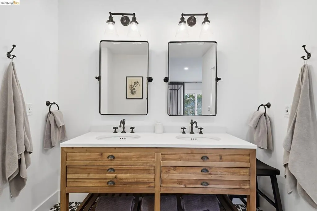 Double vanity with wood-finish cabinetry, white countertop, and dual rectangular mirrors Double vanity with wood-finish cabinetry, white countertop, and dual rectangular mirrors