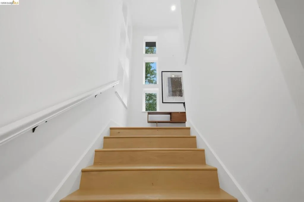 Hardwood stairs with a white handrail, recessed lighting, and multiple transom windows Hardwood stairs with a white handrail, recessed lighting, and multiple transom windows