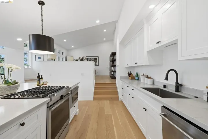Spacious kitchen featuring white cabinetry, light countertops, wood-finish flooring, and a stainless steel gas range with a matching oven