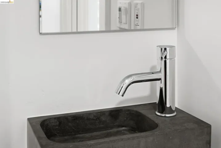 Wall-mounted rectangular mirror, chrome single-handle faucet, and dark vessel sink