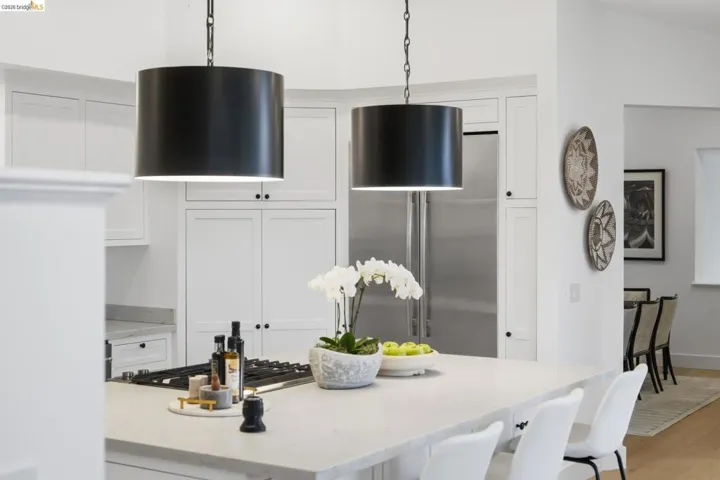Kitchen island with integrated cooktop, stone countertop, and two pendant light fixtures