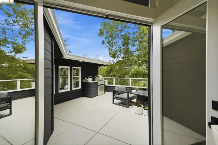 Expansive outdoor patio with concrete flooring, integrated grilling station, and a white railing system