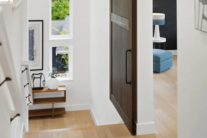 Hardwood flooring, painted white walls, natural light from multiple windows, and a dark wood-finish barn door