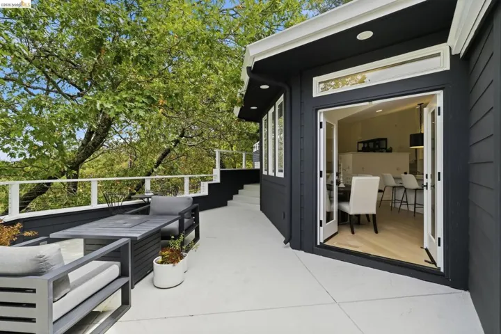 Expansive exterior deck space with white railings, a dark gray siding facade, and multiple windows