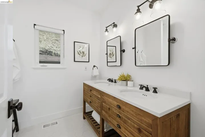 Double vanity with wood-finish cabinetry, integrated dual sinks, and white countertops