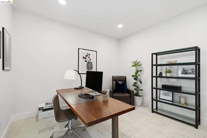 Recessed lighting, light-toned carpeting, and a built-in metal and glass shelving unit
