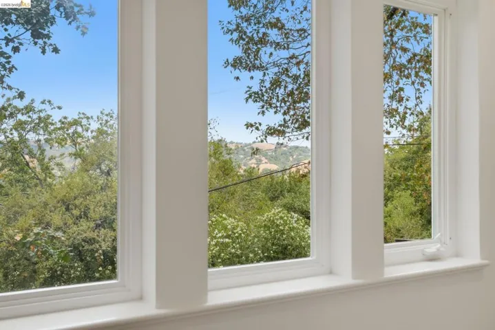 Multiple windows with white frames and sills, offering natural light and a landscape backdrop