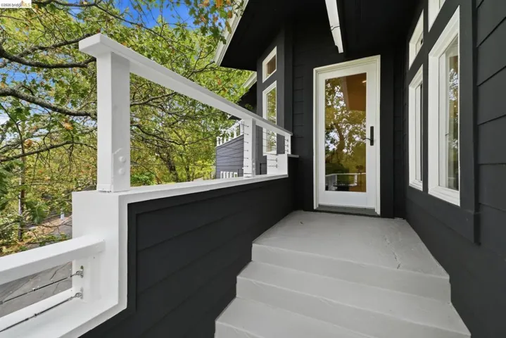 Exterior featuring dark horizontal siding, white trim windows, white full-lite entry door, and a white cable railing system