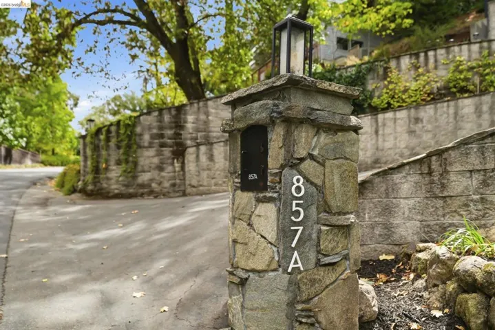 Stone-clad pillar with integrated mailbox and house numbers, featuring a dark-finish outdoor lantern