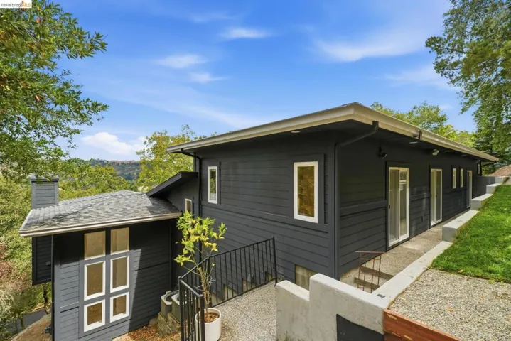 Modern siding with crisp white trim, multiple glass sliding doors, and a terraced concrete pathway