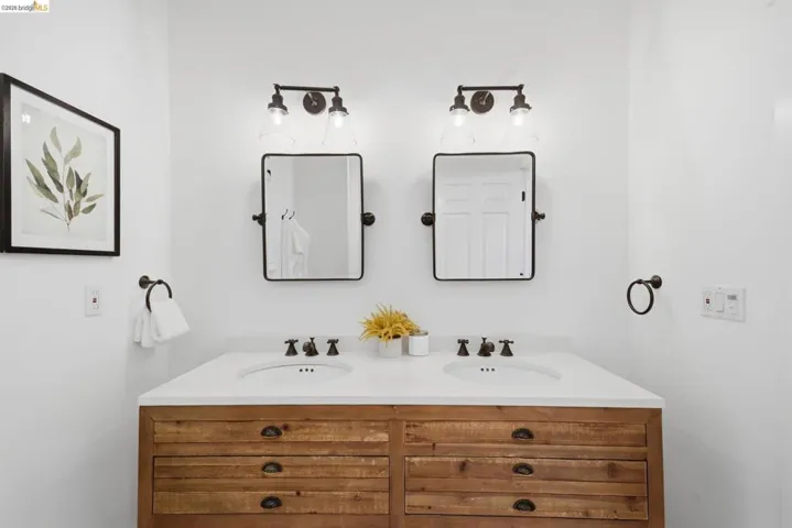 Dual sink vanity with a light wood-finish base, white countertop, and dark-finish hardware
