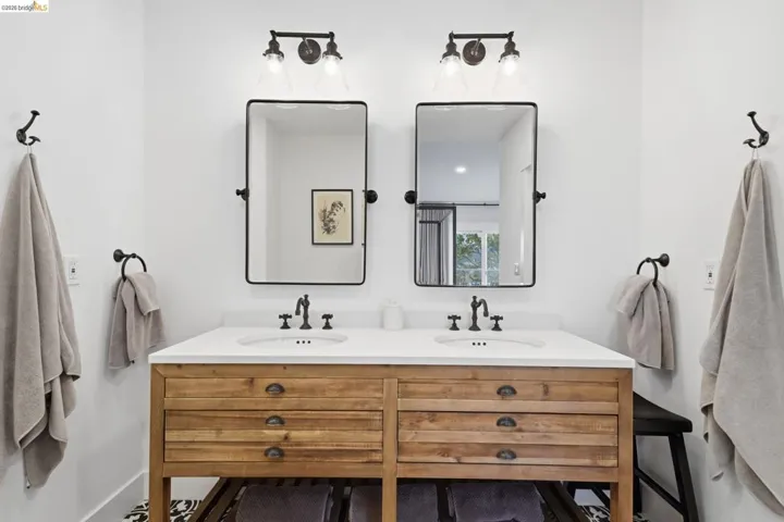 Double vanity with wood-finish cabinetry, white countertop, and dual rectangular mirrors