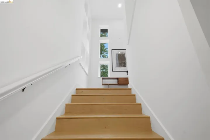 Hardwood stairs with a white handrail, recessed lighting, and multiple transom windows