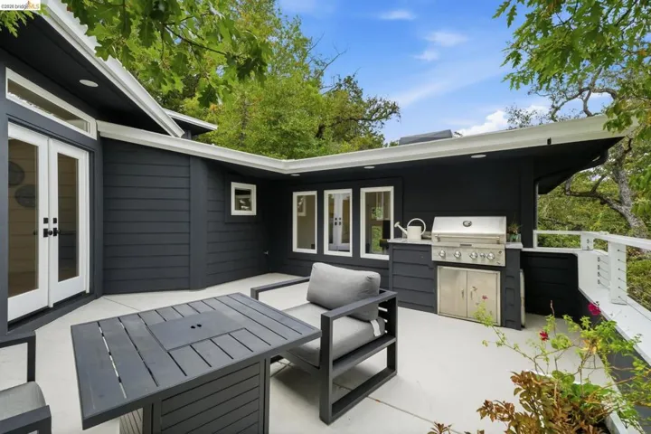 Expansive outdoor patio with dark horizontal siding, white trim, and a built-in stainless steel grill