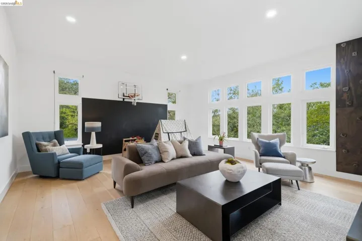 Spacious room featuring light wood-finish flooring, recessed lighting, and a large chalkboard wall