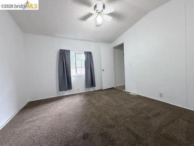 Unfurnished bedroom featuring a textured ceiling, carpet flooring, a closet, lofted ceiling, and a ceiling fan Unfurnished bedroom featuring a textured ceiling, carpet flooring, a closet, lofted ceiling, and a ceiling fan