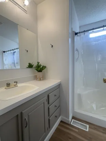 Bathroom with a textured ceiling, a shower with curtain, vanity, and dark wood-type flooring
