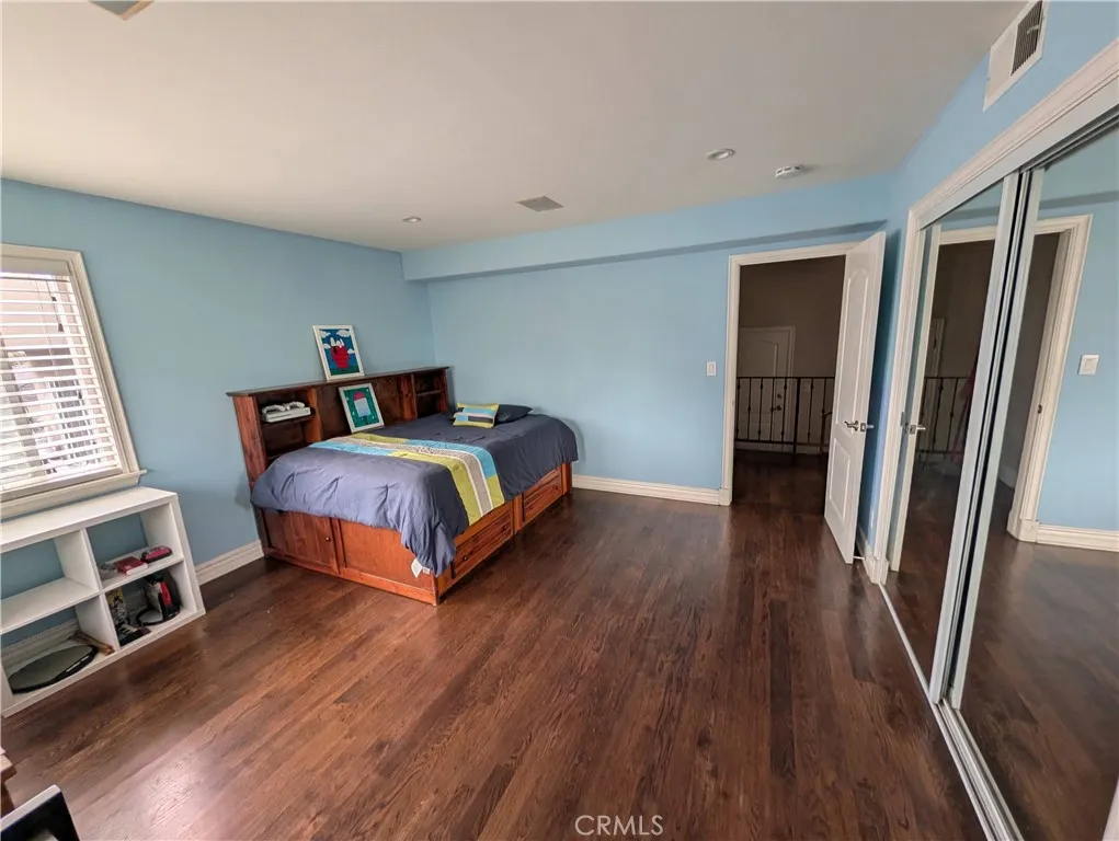 Bright third bedroom, featuring mirrored closet doors and ample space for comfortable living.