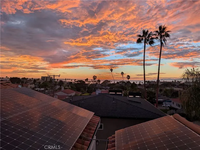 Sweeping rooftop view beneath a dramatic coastal sunset sky.