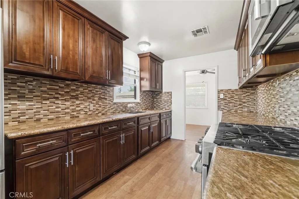 Kitchen with granite counters, rich wood cabinets and glass tile backsplash