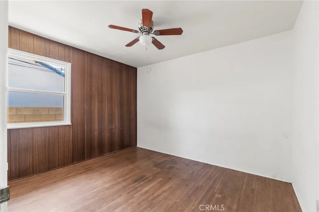 Third bedroom with wood paneling and ceiling fan