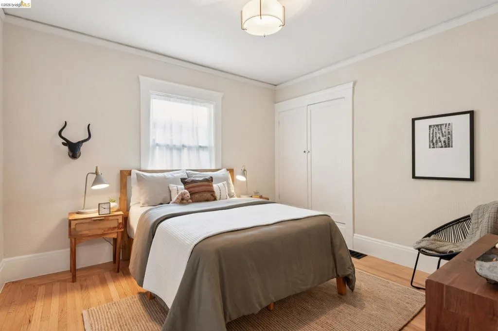 Wood-finish flooring, single window with trim, built-in closet, and ceiling-mounted light fixture Wood-finish flooring, single window with trim, built-in closet, and ceiling-mounted light fixture