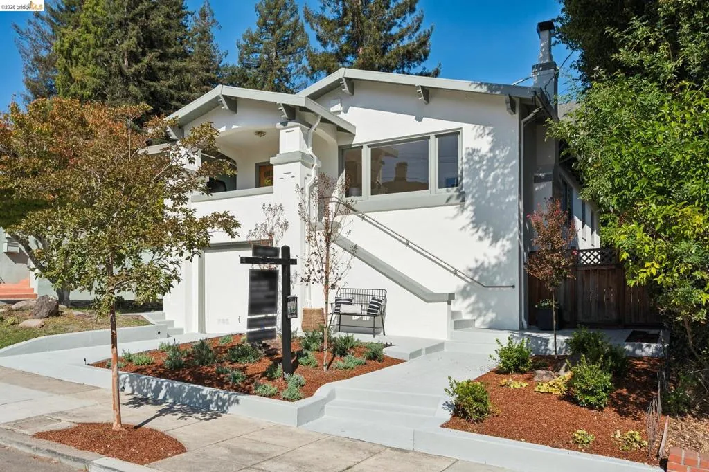 White stucco exterior with gray trim, multiple windows, and a prominent chimney White stucco exterior with gray trim, multiple windows, and a prominent chimney