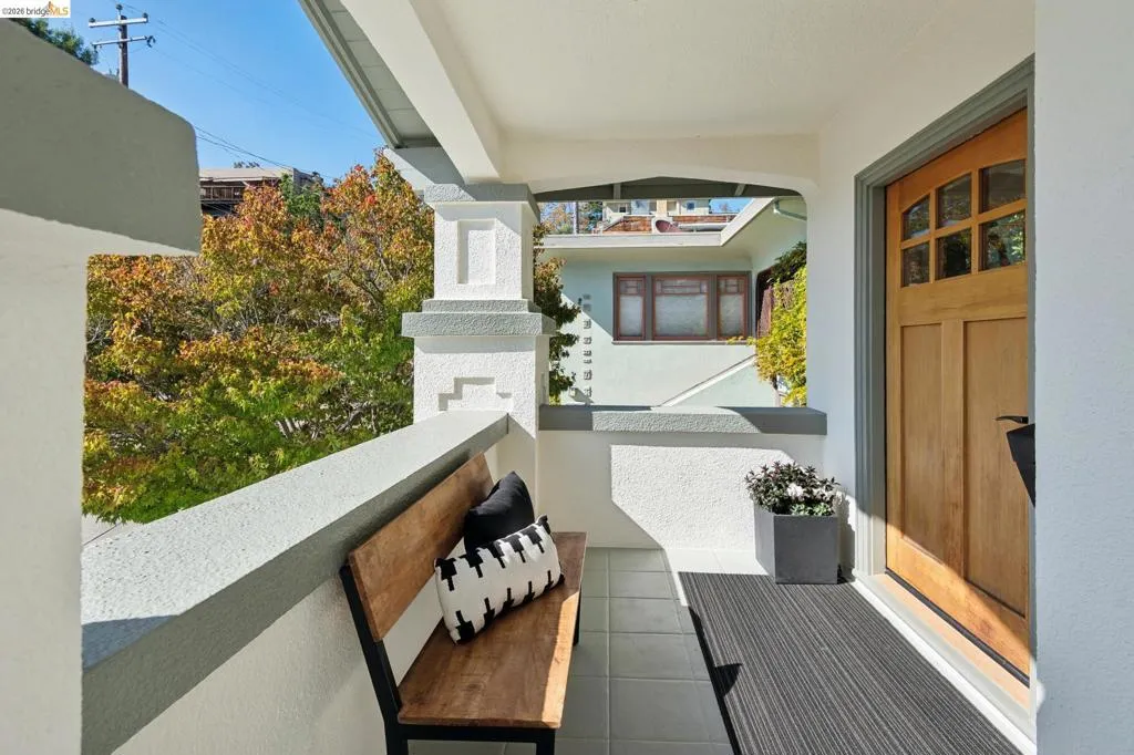 Covered front porch featuring a wood-panel entry door with glass inserts, tiled flooring, and decorative architectural columns Covered front porch featuring a wood-panel entry door with glass inserts, tiled flooring, and decorative architectural columns