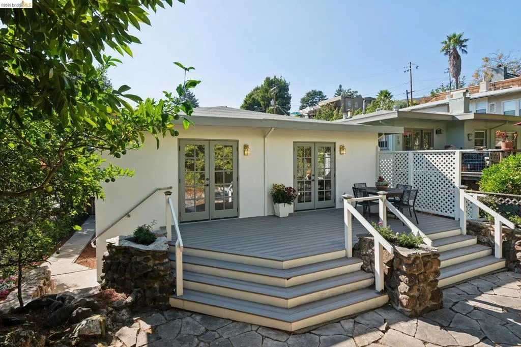 Spacious exterior deck with composite flooring, stone-clad stairs, and white railing Spacious exterior deck with composite flooring, stone-clad stairs, and white railing
