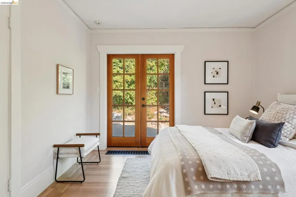 Wood-finish flooring with a light tone, crown molding, and wooden French doors Wood-finish flooring with a light tone, crown molding, and wooden French doors