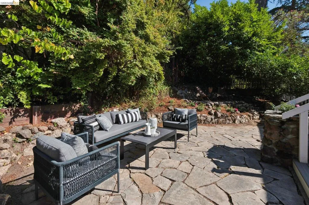Stone patio with natural stone retaining walls and abundant mature landscaping Stone patio with natural stone retaining walls and abundant mature landscaping