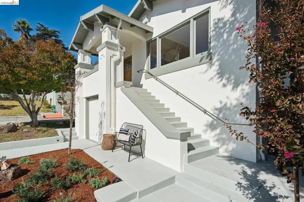 Stucco exterior featuring architectural trim details, a prominent staircase with a handrail, a wood entry door, and multi-pane windows Stucco exterior featuring architectural trim details, a prominent staircase with a handrail, a wood entry door, and multi-pane windows