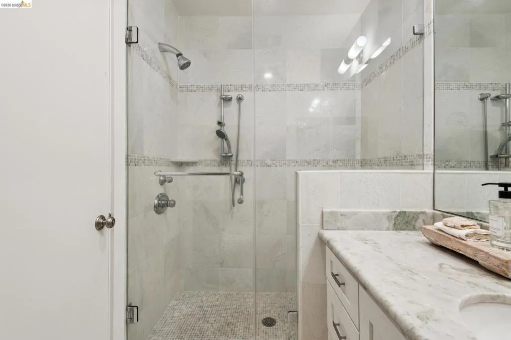 Glass-enclosed shower with tile surround and mosaic accent bands Glass-enclosed shower with tile surround and mosaic accent bands