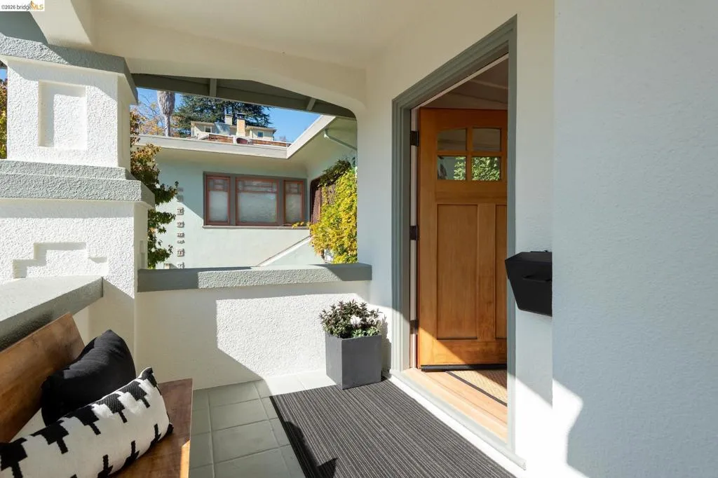 Covered entry with tiled flooring, a natural wood paneled door with glass inserts, and a black wall-mounted mailbox Covered entry with tiled flooring, a natural wood paneled door with glass inserts, and a black wall-mounted mailbox