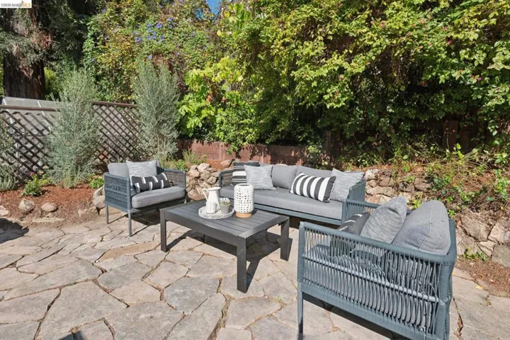 Flagstone patio with a trellised fence and lush perimeter landscaping