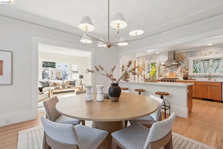 Open concept living spaces with wood-finish flooring, a contemporary chandelier, a kitchen island with seating, and stainless steel appliances
