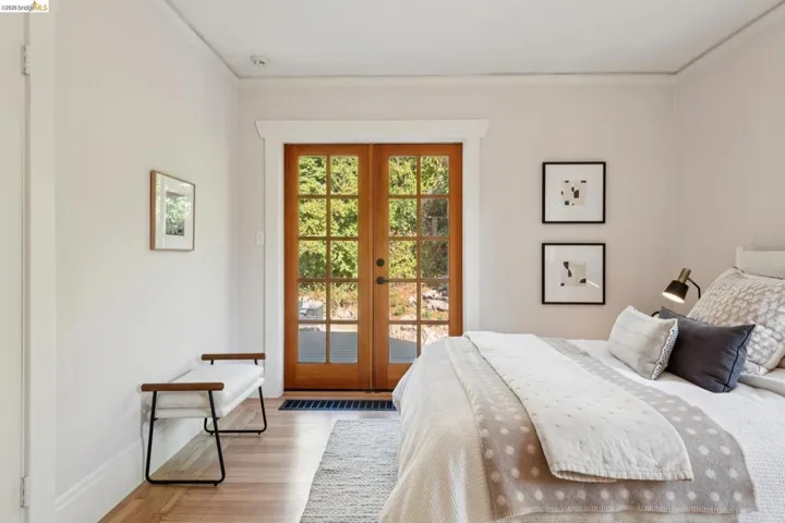 Wood-finish flooring with a light tone, crown molding, and wooden French doors