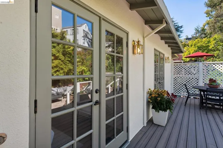 Exterior featuring French doors, a composite deck, decorative wall lattice, and an exterior wall lantern