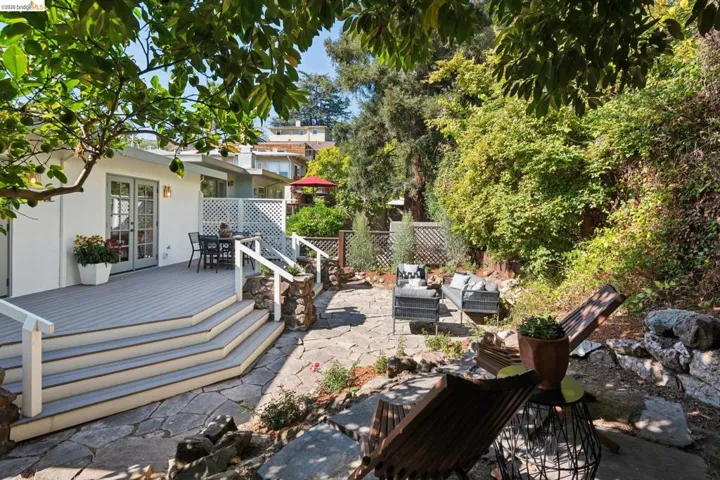 Expansive flagstone patio with a multi-level deck featuring white railings and a lattice privacy screen