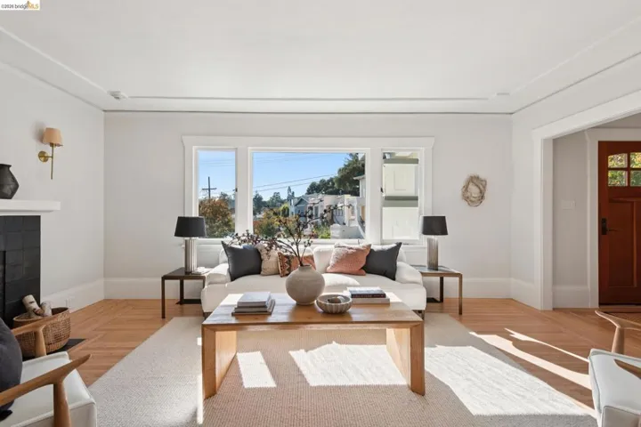Hardwood flooring throughout, a fireplace with a black tile surround, a built-in mantel, and decorative ceiling trim
