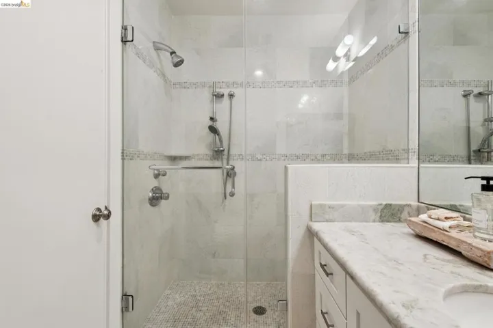 Glass-enclosed shower with tile surround and mosaic accent bands