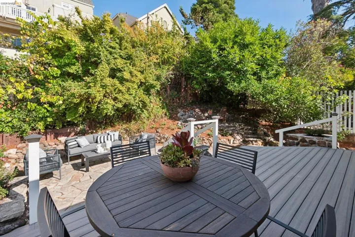 Expansive outdoor living area featuring a multi-level deck, stone patio, and natural landscaping with mature foliage