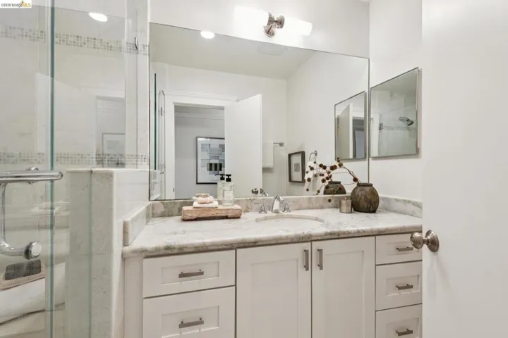 Vanity with a built-in sink, stone countertop, and white cabinetry