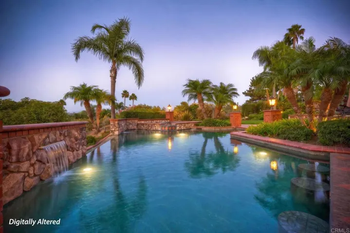 Amazing pool with water features, pool lighting & 4 built in bar stools next to outdoor kitchen.