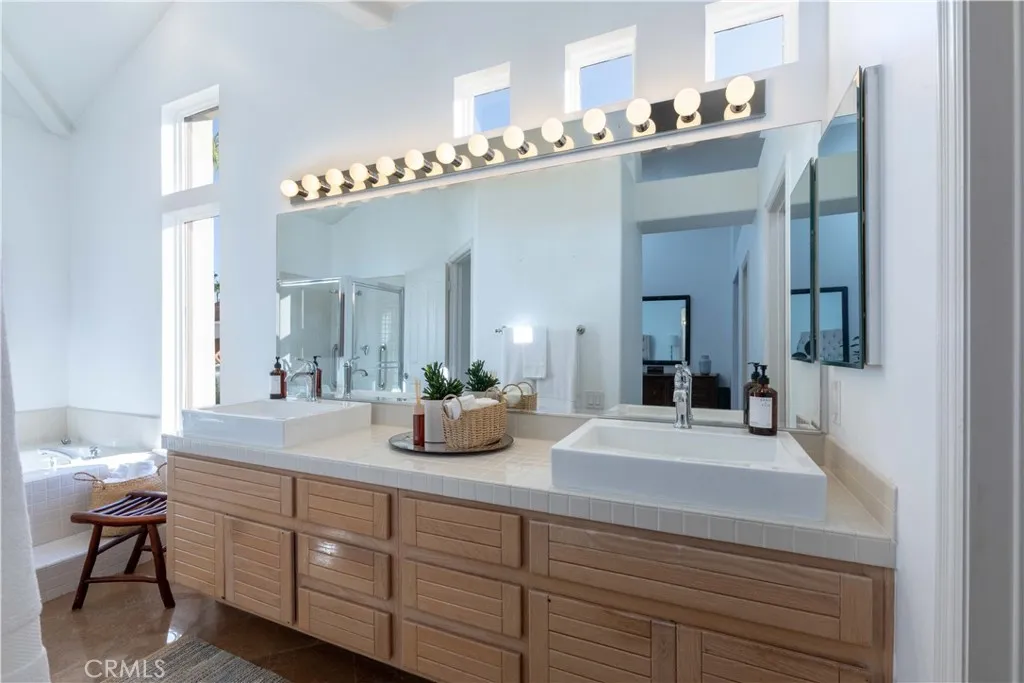 Primary bath has double sinks, a vanity bath bar light fixture, and a sunken bathtub