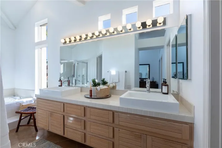 Primary bath has double sinks, a vanity bath bar light fixture, and a sunken bathtub
