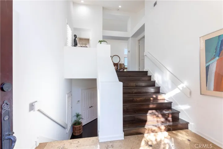 Wide staircase at main entry leading up to the Top Level with Main Living, Dining, Kitchen Level with Primary Bedroom and Bath and Guest Powder Room